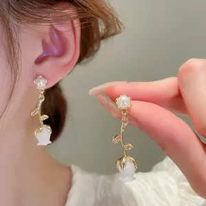 Elegant pearl flower drop earrings detail shot, showing delicate gold metal craftsmanship.