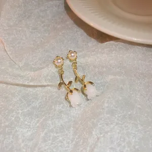 Delicate gold-tone flower pendant earrings with pearl accent, elegant and charming detail shot.