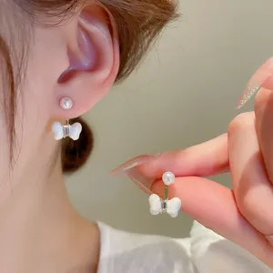 Exquisite pearl and white bow earrings detail, elegant ear stud design for women everyday wear.