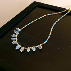 Vue détaillée d'un collier de perles coloré à la mode avec des pendentifs en cristal.