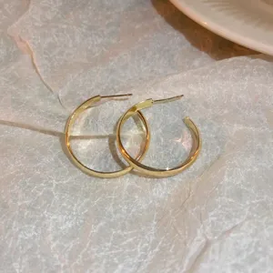 Close-up detail shot of minimalist gold hoop earrings showcasing sleek metallic shine and polished finish.
