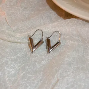 Detail view of stylish silver-toned V-shaped hoop earrings on textured white paper background.