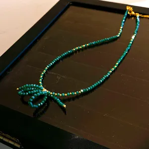 Détail du collier nœud en perles vertes, élégantes perles de cristal émeraude avec détails dorés.