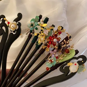 Primo piano di forcine per capelli in legno vintage con coniglio di giada e bei fiori.