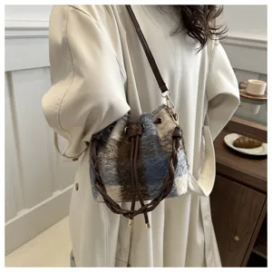 Detail close-up shot of fuzzy plaid bucket bag featuring a brown braided handle and strap.