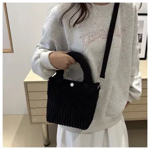 Dettaglio borsa a secchiello in velluto a coste nero con morbida texture e tracolla per uso.