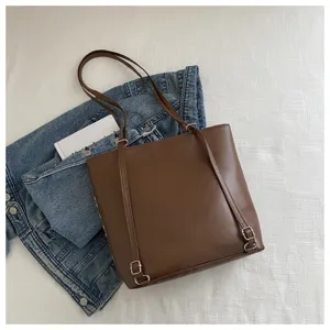 Detail view of the stylish brown PU leather tote bag with convertible straps and metallic hardware.