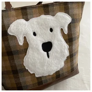 Detail shot of women wool plaid tote bag with cute white fluffy dog plush applique patch.