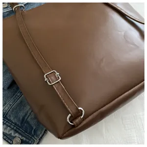 Brown PU leather tote bag backpack detail showing metal buckle strap and fine stitching design.