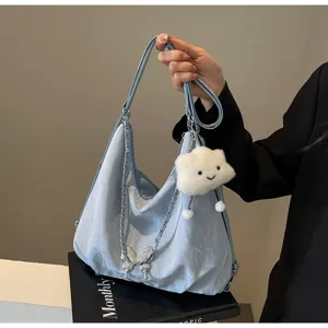 Detailed view of casual soft blue shoulder dumpling bag with cute butterfly chain and cloud pendant.