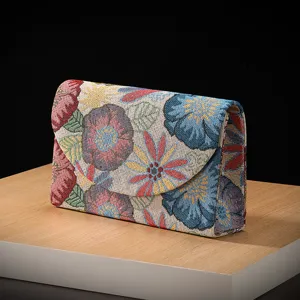Close-up detail of vintage jacquard floral envelope clutch bag with elegant woven fabric pattern.