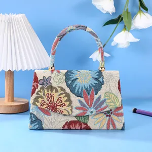 Detailed view of vintage woven floral handbag showing colorful fabric texture and handle craftsmanship.