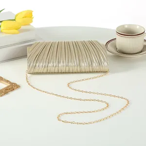 Gold pleated evening clutch bag detail view featuring metallic texture and delicate chain strap.