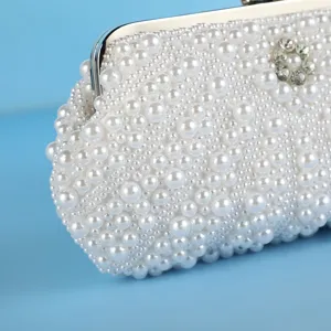 Detailed view of white pearl beaded evening clutch bag featuring metal clasp and floral rhinestone.