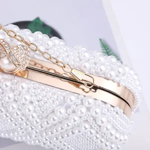 Detailed shot of elegant pearl evening clutch bag with gold chain and rhinestone clasp.