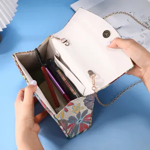 Woven floral crossbody handbag interior detail showing compartment and chain strap.