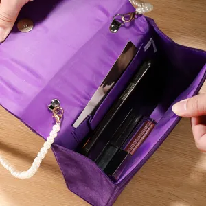 Purple satin evening clutch bag with elegant pearl strap and spacious interior compartment.