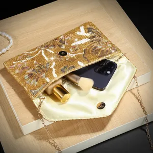 Bolso de noche dorado con pedrería, correa de cadena y vista interior que muestra la capacidad.