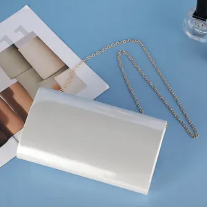 Silver patent leather evening clutch bag with golden chain strap for women banquet events.
