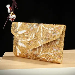 Detalle de bolso de mano de noche con cuentas artesanales y delicado diseño floral de lentejuelas.