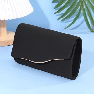 Dettaglio borsa da sera in velluto nero, consistenza morbida con elegante bordo dorato.