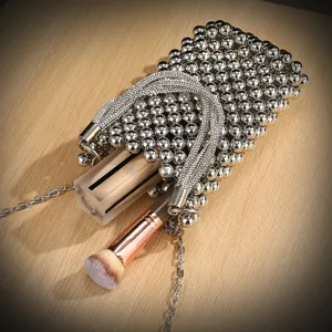 Detail shot of sparkling beaded phone bag with rhinestone handle and metal chain strap.