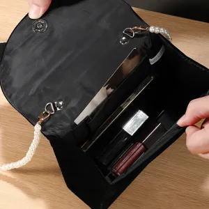 Black velvet evening clutch bag with elegant pearl chain strap, interior storage pocket.