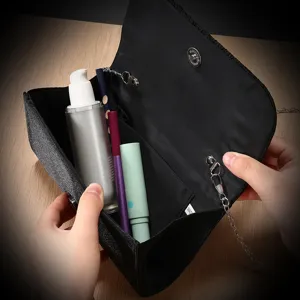 Black evening bag detail showing interior capacity, structure and magnetic clasp design