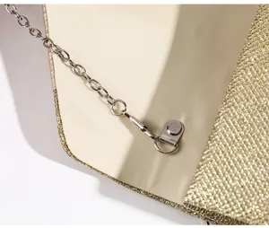 Dettaglio borsa da sera dorata con cinturino a catena di metallo e fodera di chiusura magnetica.