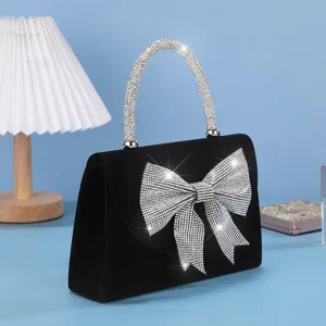 Elegant black velvet evening bag with sparkling crystal bow and handle for party dress.