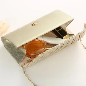 Close-up detail of luxury gold pleated evening clutch bag with delicate chain strap and snap.