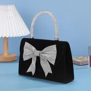 Elegant black velvet evening bag featuring sparkling rhinestone bow and crystal top handle.