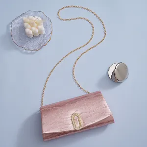 Close-up detail of the pink metallic evening bag featuring a sparkling rhinestone buckle.