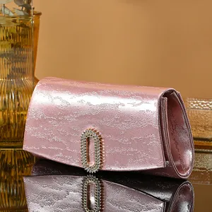 Close-up detail of the pink evening clutch featuring a sparkling rhinestone oval clasp design.