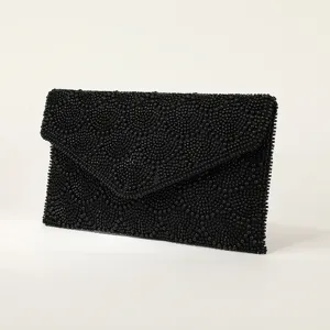Vista dettagliata della elegante pochette da sera nera perlinata con delicati motivi.