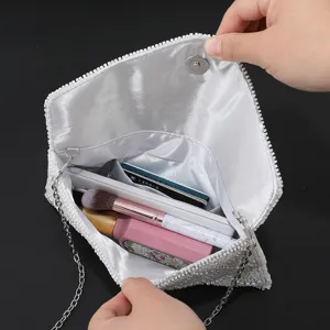Vista dettagliata della borsa da sera bianca con perline, capienza interna e catena.
