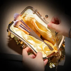 Primo piano di una glamour pochette da sera in paillettes dorate con struttura in metallo e raso.