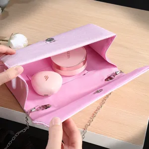 Pink pleated satin evening clutch bag interior detail showing chain strap and storage space.