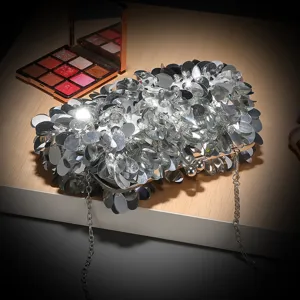 Vista dettagliata della borsa pochette da sera in paillettes argentate con chiusura e catena.