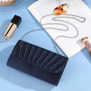 Detailed view of elegant navy blue pleated evening clutch bag featuring a sleek silver chain strap.