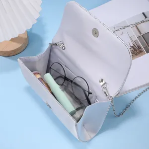 Silver evening clutch bag detail view, featuring metallic chain strap and open interior layout.