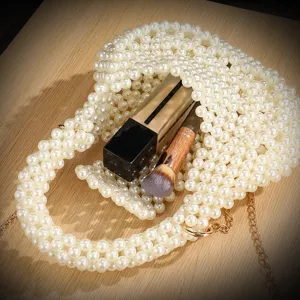 Handmade pearl beaded evening bag detail, white artificial pearls and gold chain accent.