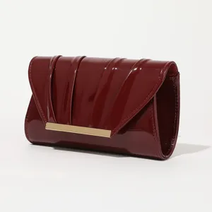 Elegant dark red patent leather clutch bag with chic pleated design and gold metal bar detail.