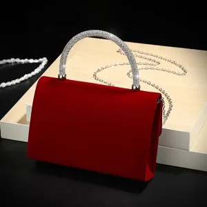 Red velvet evening bag detail, sparkling rhinestone handle and gold chain display close up