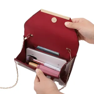 Wine red patent leather clutch bag with gold chain strap, envelope design for evening parties.