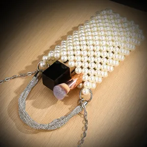 Close-up detail of a pearl beaded phone bag with rhinestone handle and metal chain strap.