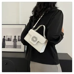 Elegante bolso de mano de cuero blanco con hebilla cuadrada de pedrería brillante.