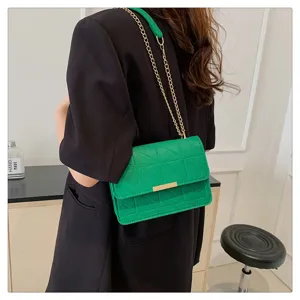 Detalle de bolso bandolera de fieltro verde con cadena dorada y cierre metálico elegante.