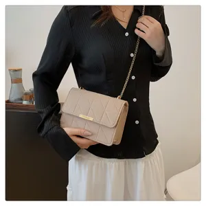 Primer plano del bolso cruzado de fieltro beis con cadena y cierre, estilo elegante.