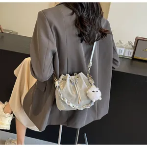 Detalle de bolso saco metalizado plateado con asa trenzada, cordón ajustable y abalorio.